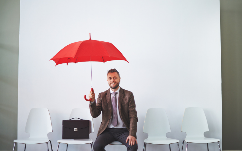Man sitting under red umbrella