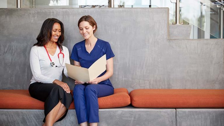 two female medical professionals sitting and reading document