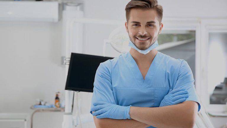 Smiling young dentist in scrubs