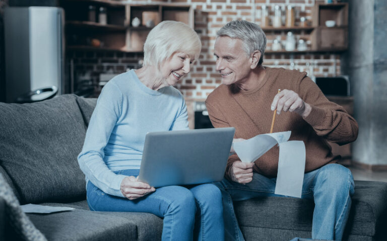 Older couple sat on sofa with laptop