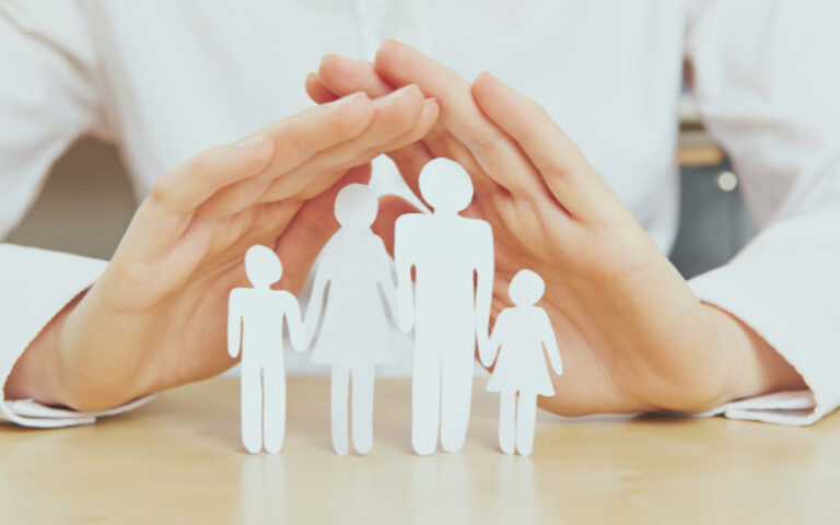 Hands covering paper family cutouts