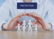 Hands sheltering paper cut-out family